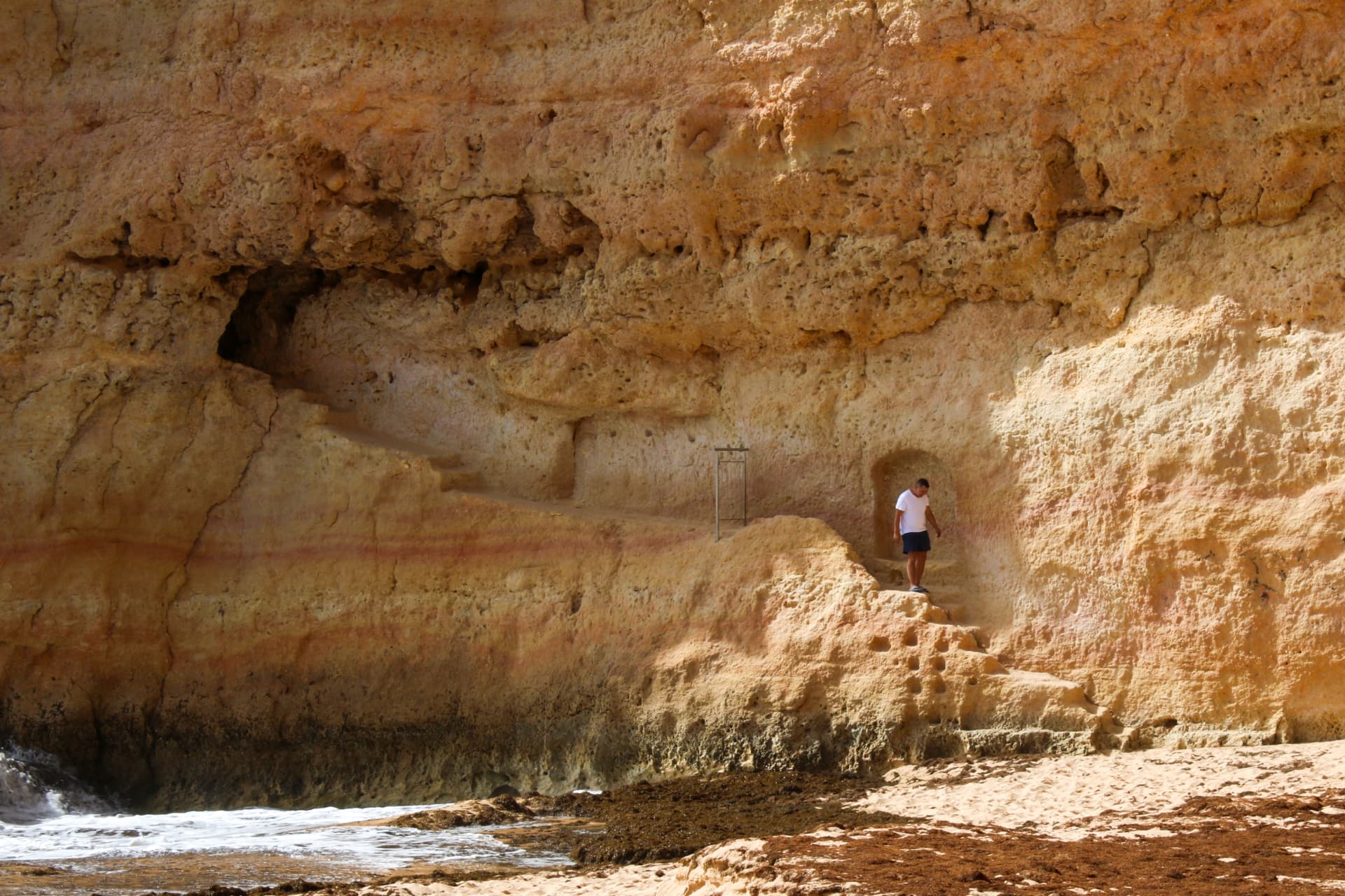 Paisaje rocoso del Algarve con una pequeña figura humana entre las formaciones naturales.