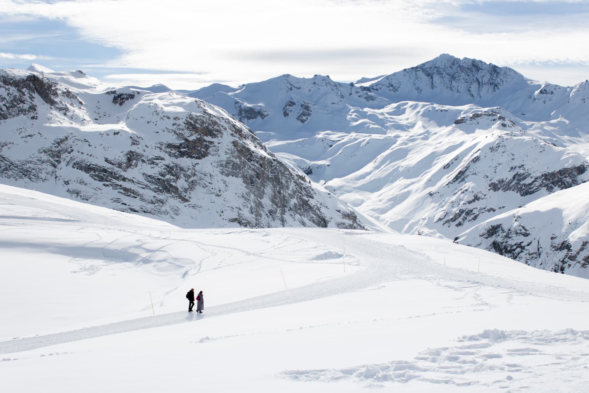 Amplio paisaje nevado de Val d’Isère con dos pequeñas figuras humanas.