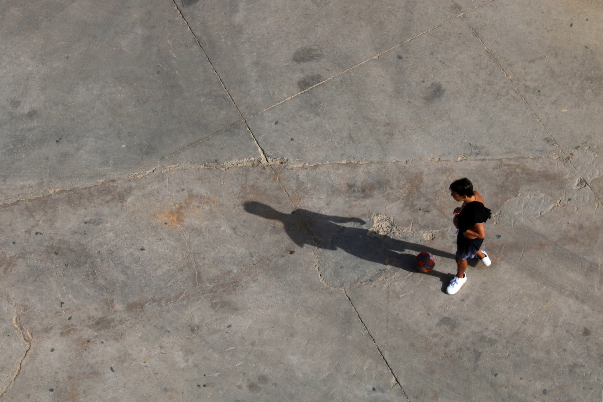 Figura con un balón sobre una superficie urbana de hormigón en Portimão.