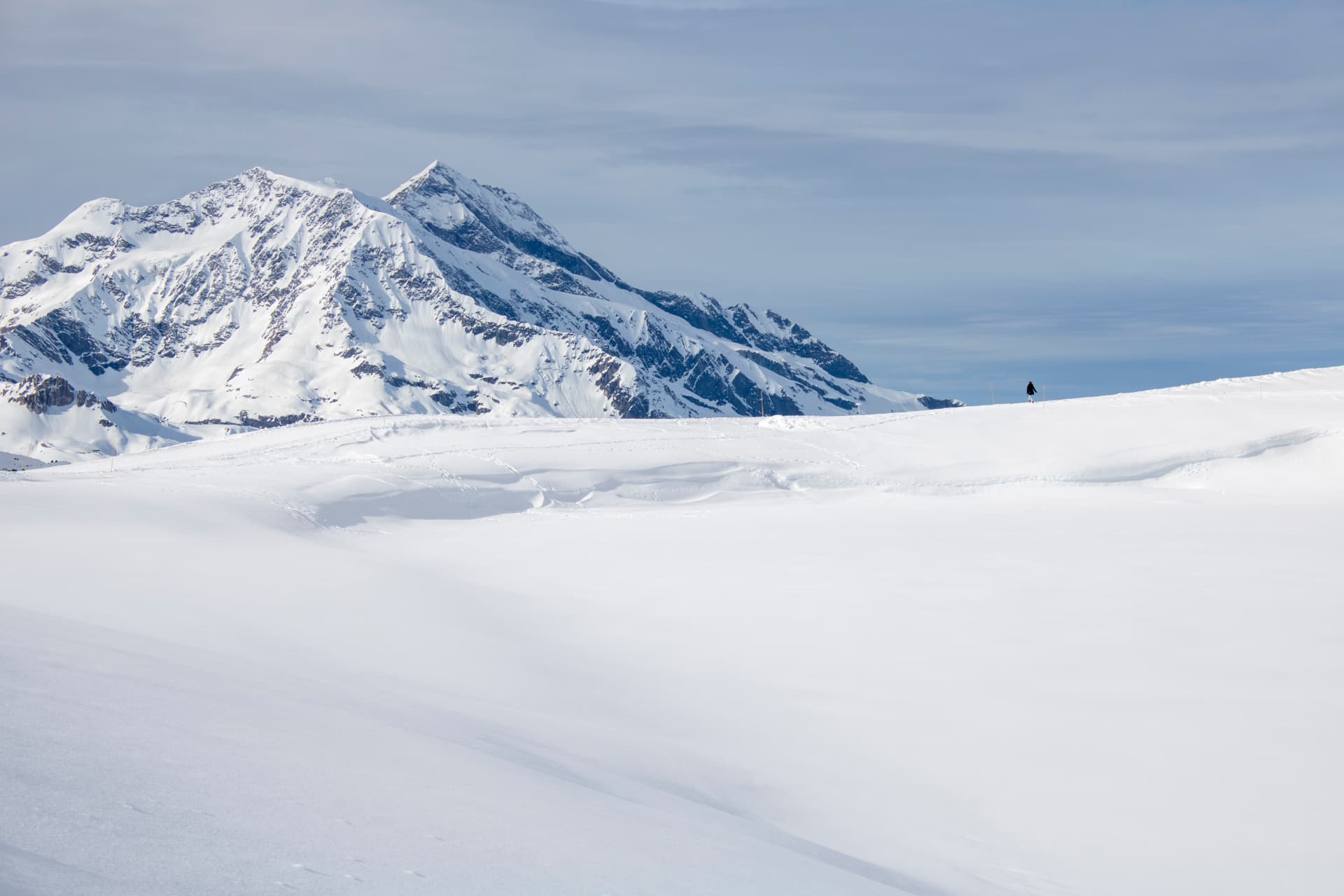 Paisaje de montaña nevado en Val d’Isère con una pequeña figura humana.